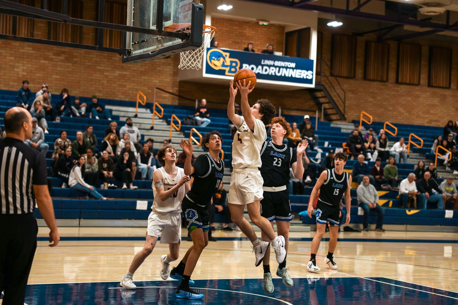 Players battle for possession during a competitive basketball game in a gymnasium.