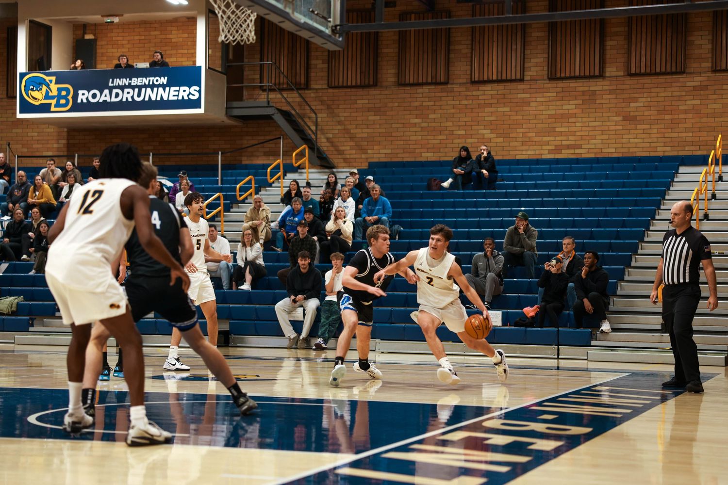 Two basketball teams face off during an intense game on a polished court with spectators watching.