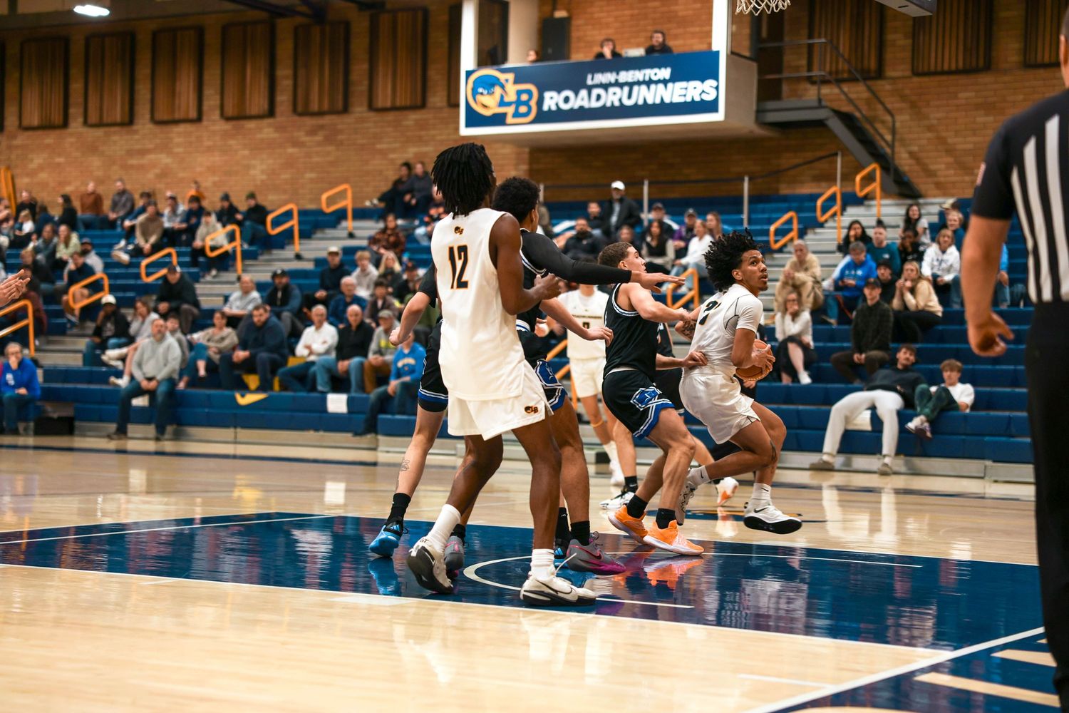 Basketball players compete for position during a fast-paced game on a blue court.