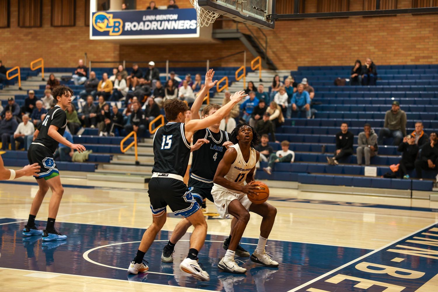 Basketball players in motion during a fast-paced game with crowd visible in stadium seating.