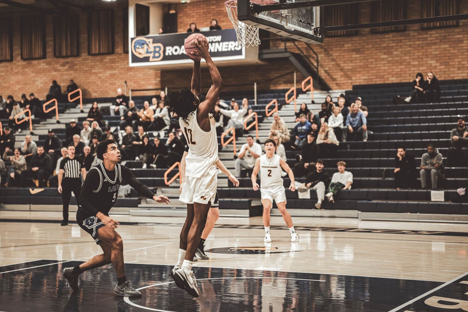 Two basketball players jump high to contest a shot near the basket.