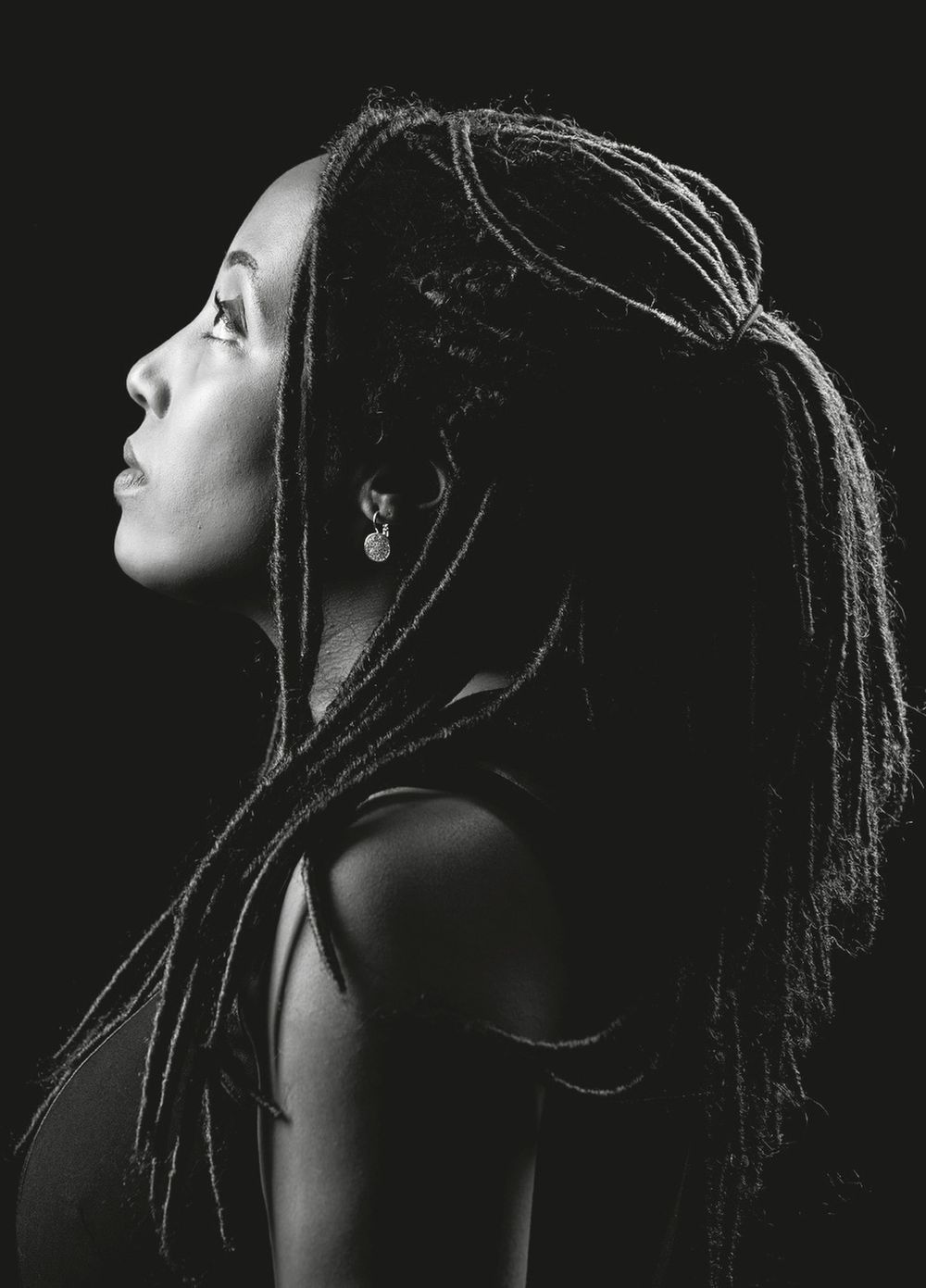 Black and white artistic portrait series showing dramatic side profile with dreadlocks against dark background.