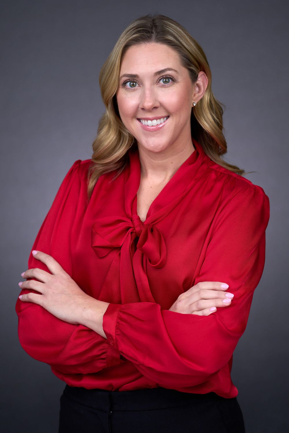 Professional headshots showing someone in a bright red blouse against a dark gray studio background.