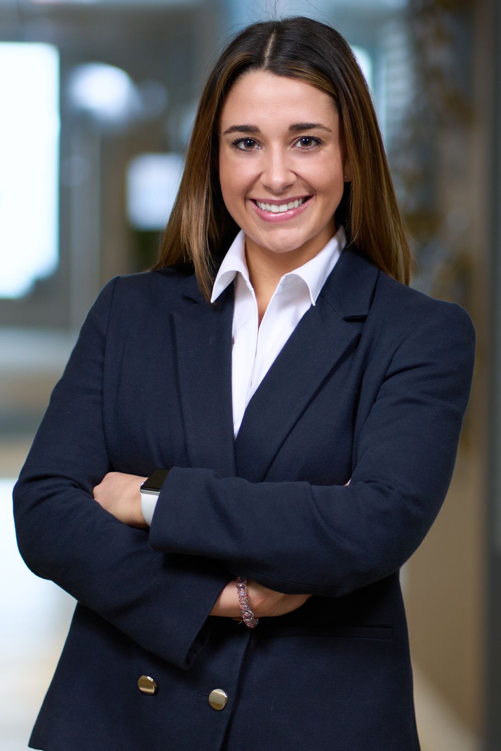 Professional business portraits of a person in a dark blazer with arms crossed and confident smile.