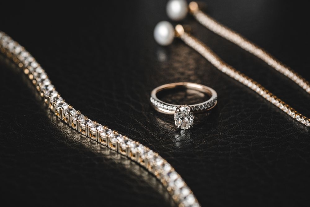 Elegant wedding jewelry and accessories arranged on dark surface with dramatic lighting.