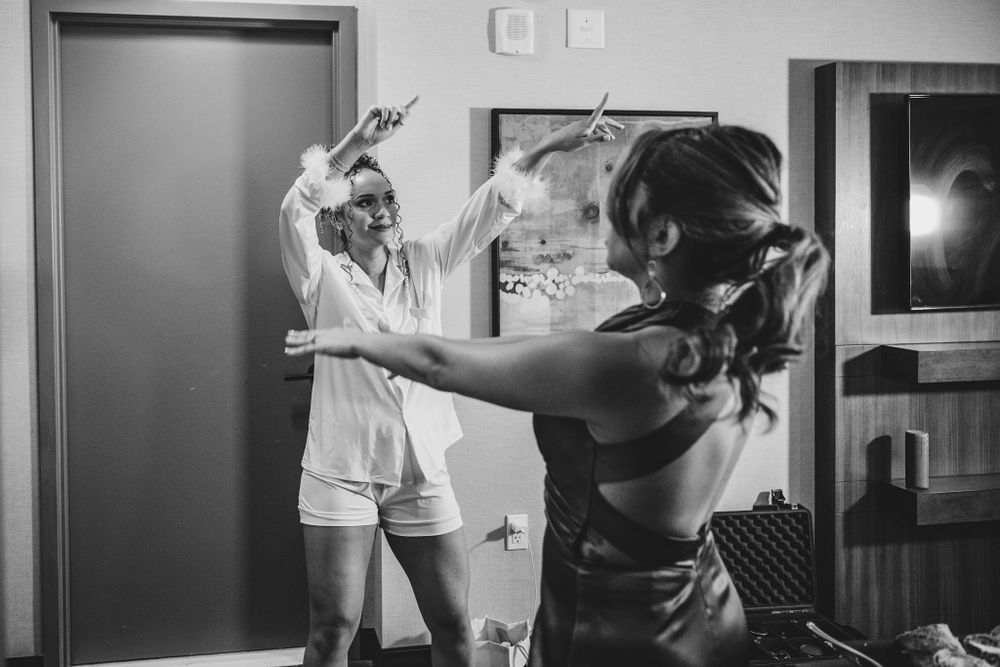 Black and white candid shot showing joyful dance moves in a hotel room.