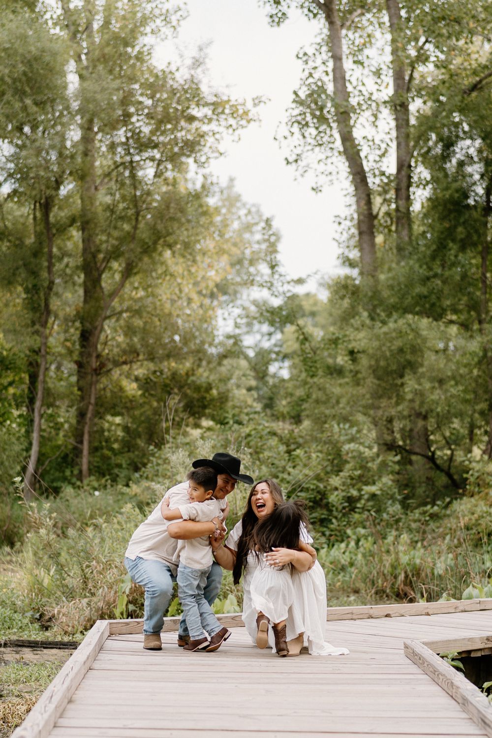A couple shares tender moments while laying on a wooden boardwalk in a natural outdoor setting.