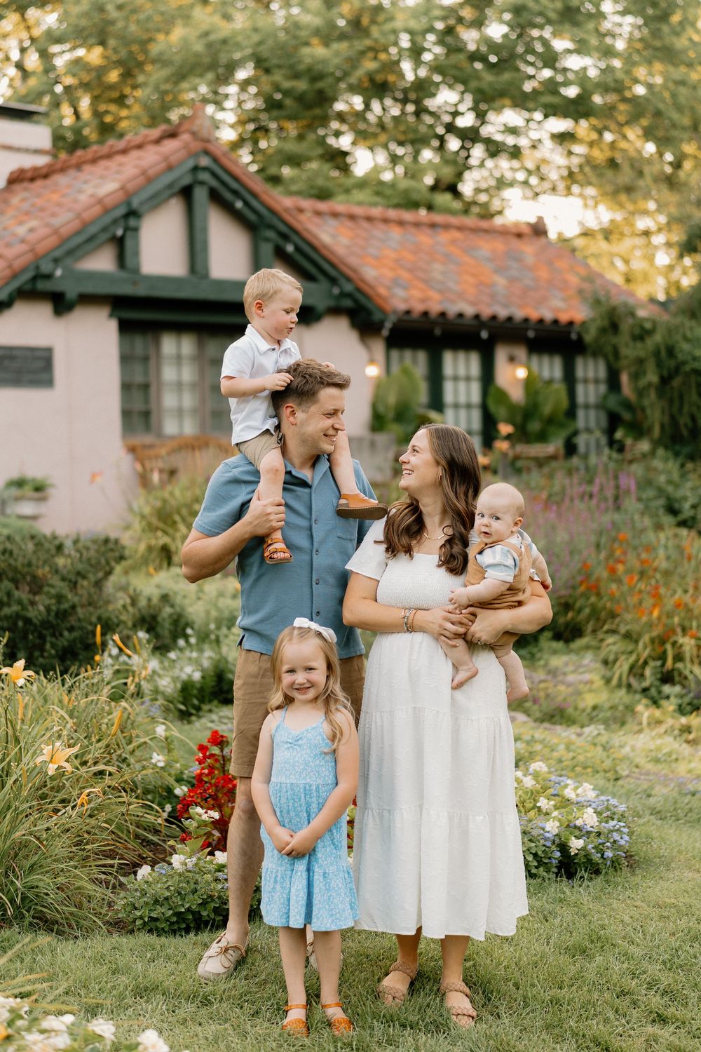 A family shares joyful moments together in a garden setting with red flowers and Spanish-style buildings in the background.