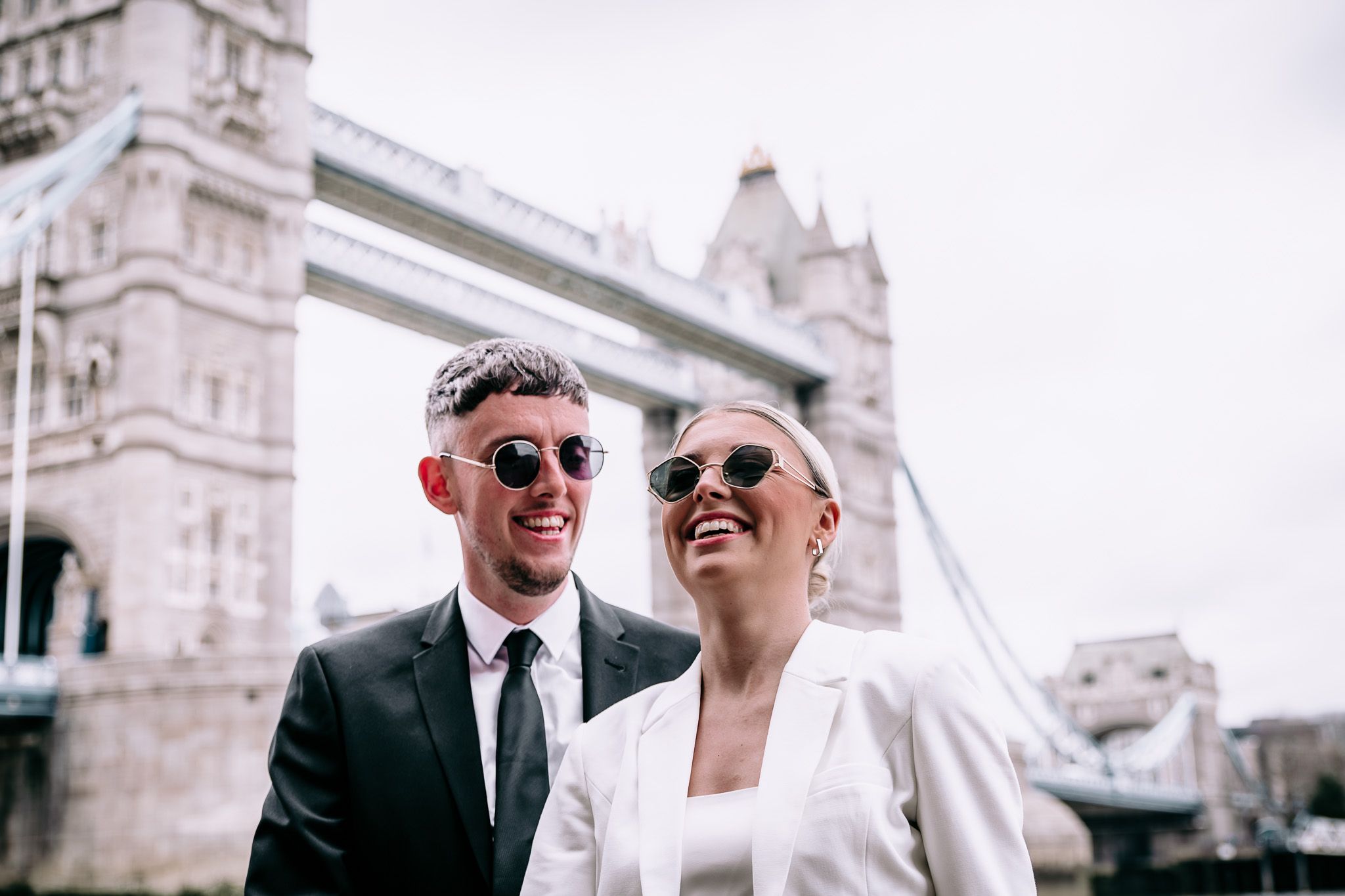 Elegant couple shares intimate moments against the backdrop of Tower Bridge in London.