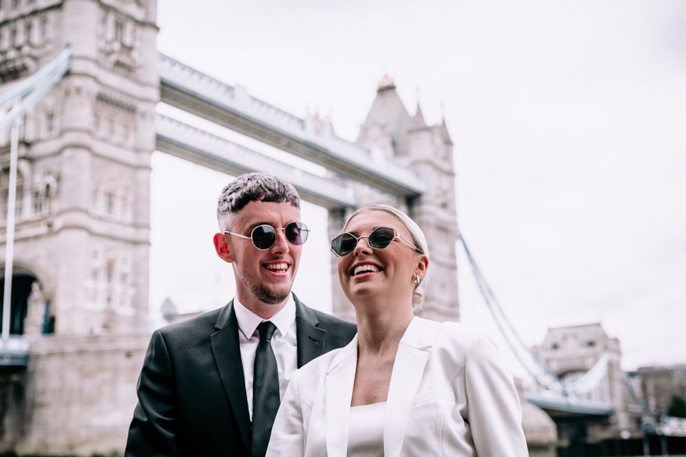 Elegant couple shares intimate moments against the backdrop of Tower Bridge in London.