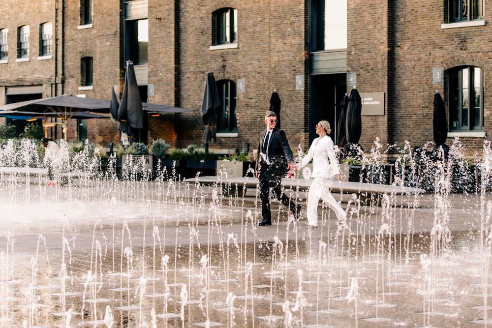 Water fountain display creates geometric patterns in front of brick building.