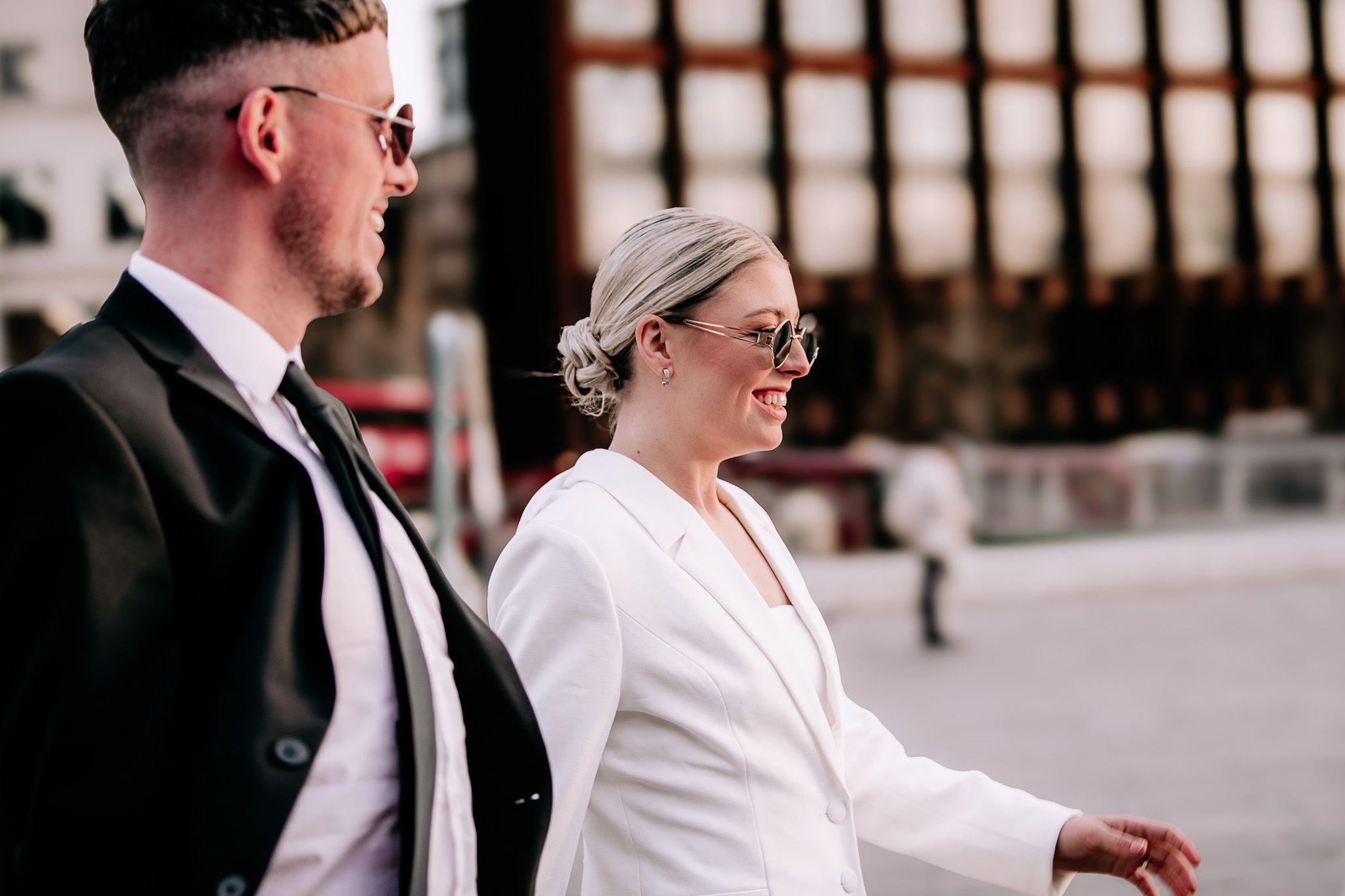 Couple in formal attire walking through urban setting.