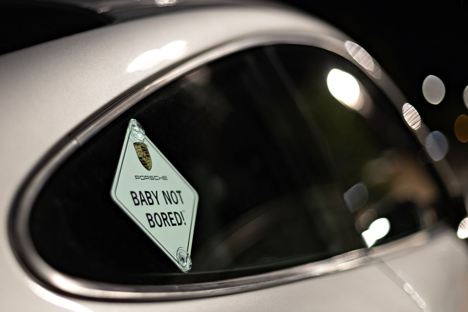Close-up of car side mirror with baby on board sign visible in reflection.