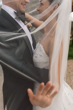 Close-up wedding photo of a couple sharing an intimate moment under a sheer white veil.