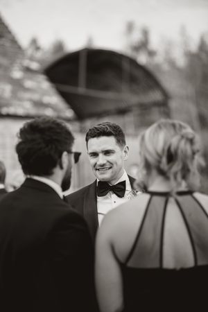 A black and white wedding photo sequence showing candid moments between guests at an outdoor celebration.