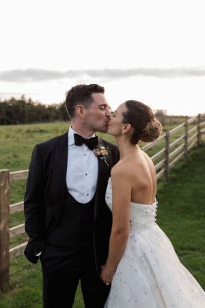 A romantic wedding couple shares intimate kisses in a series of photos taken outdoors against a rustic fence backdrop.