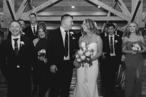 Black and white photo of a wedding celebration with bridal party members standing together in an indoor venue.