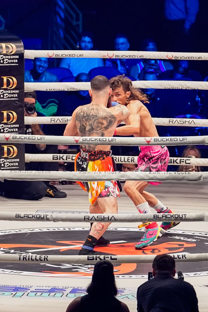 Two bare knuckle boxers trading punches in the ring under dramatic arena lighting, intense action sports photo by SRX Media Group