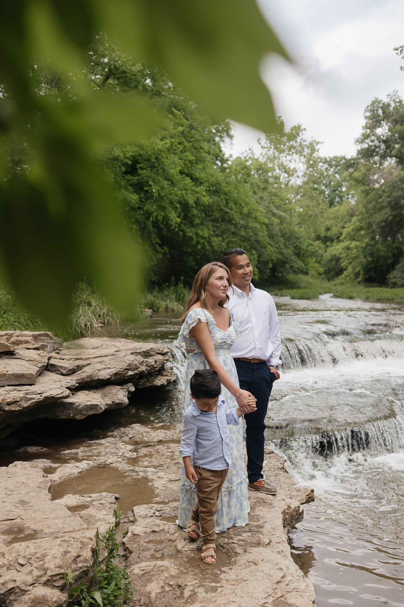 family standing by a creek bed holding hands and admiring the clouds Family photographers kansas city