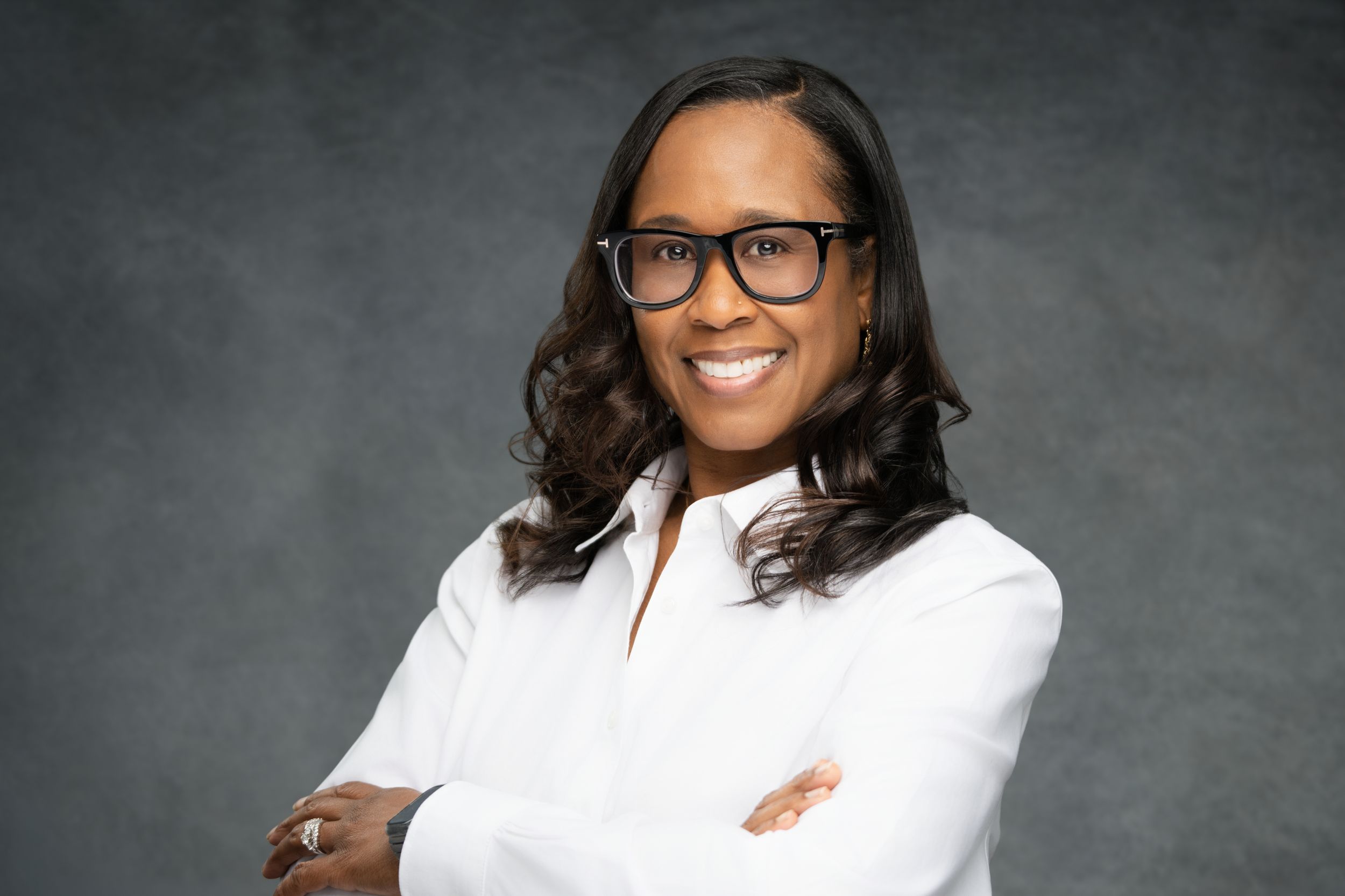 Professional headshot portraits of someone in a white blazer against a dark gray studio background.