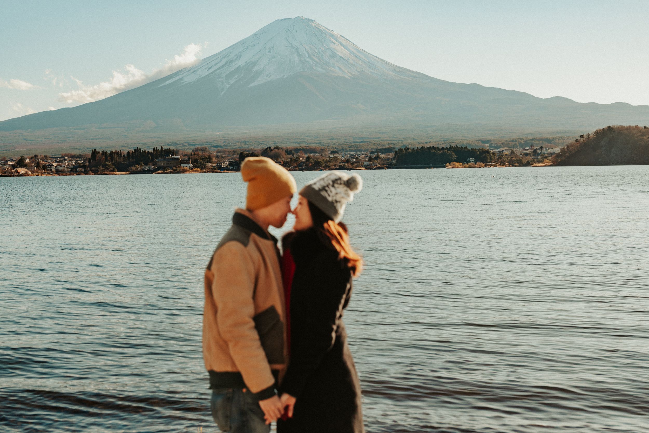 Winter scene at Lake Kawaguchiko with couple bundled up against the cold beneath snow-capped Mount Fuji.