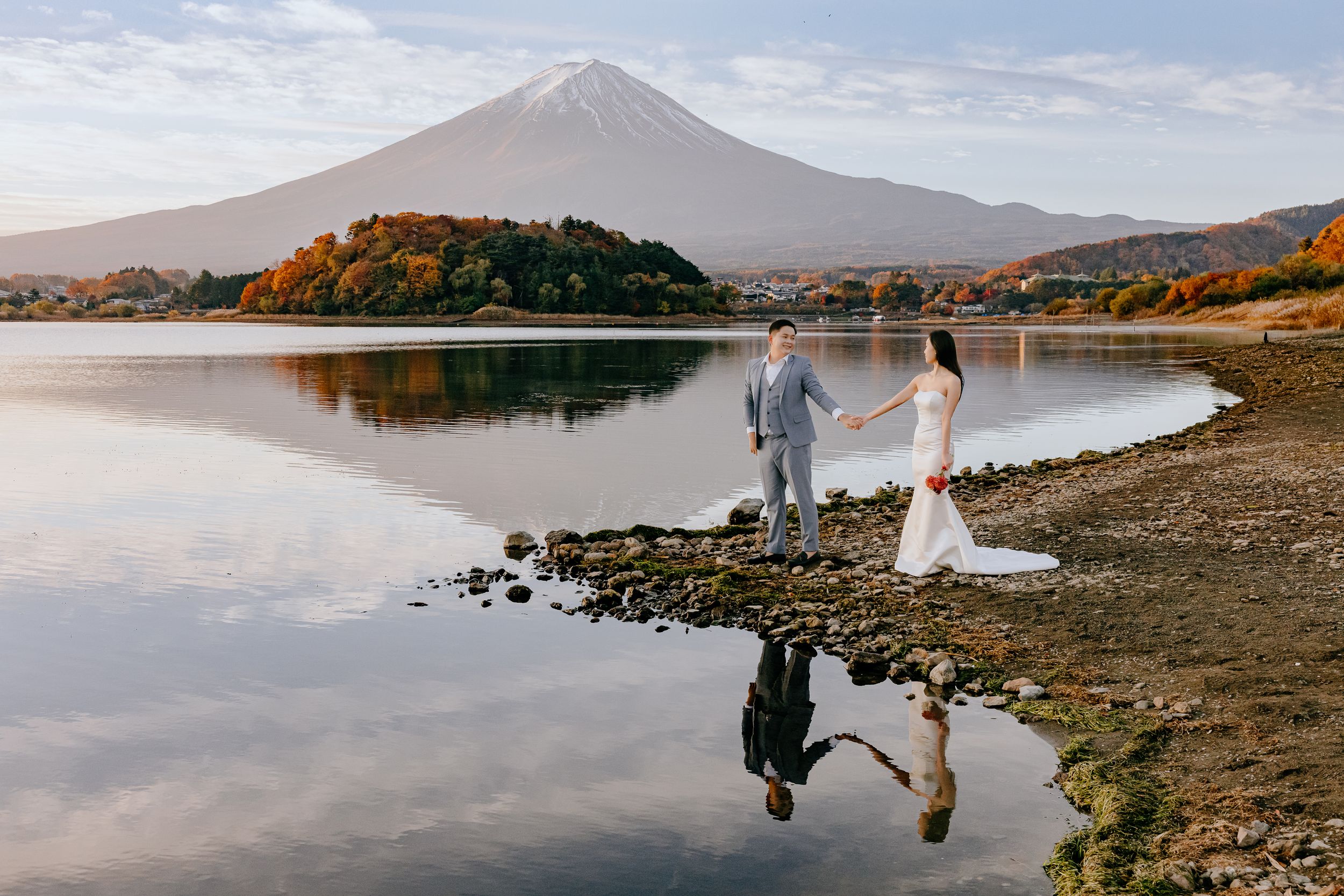 Mount Fuji rises majestically above Lake Kawaguchiko during autumn with colorful fall foliage along the shore.