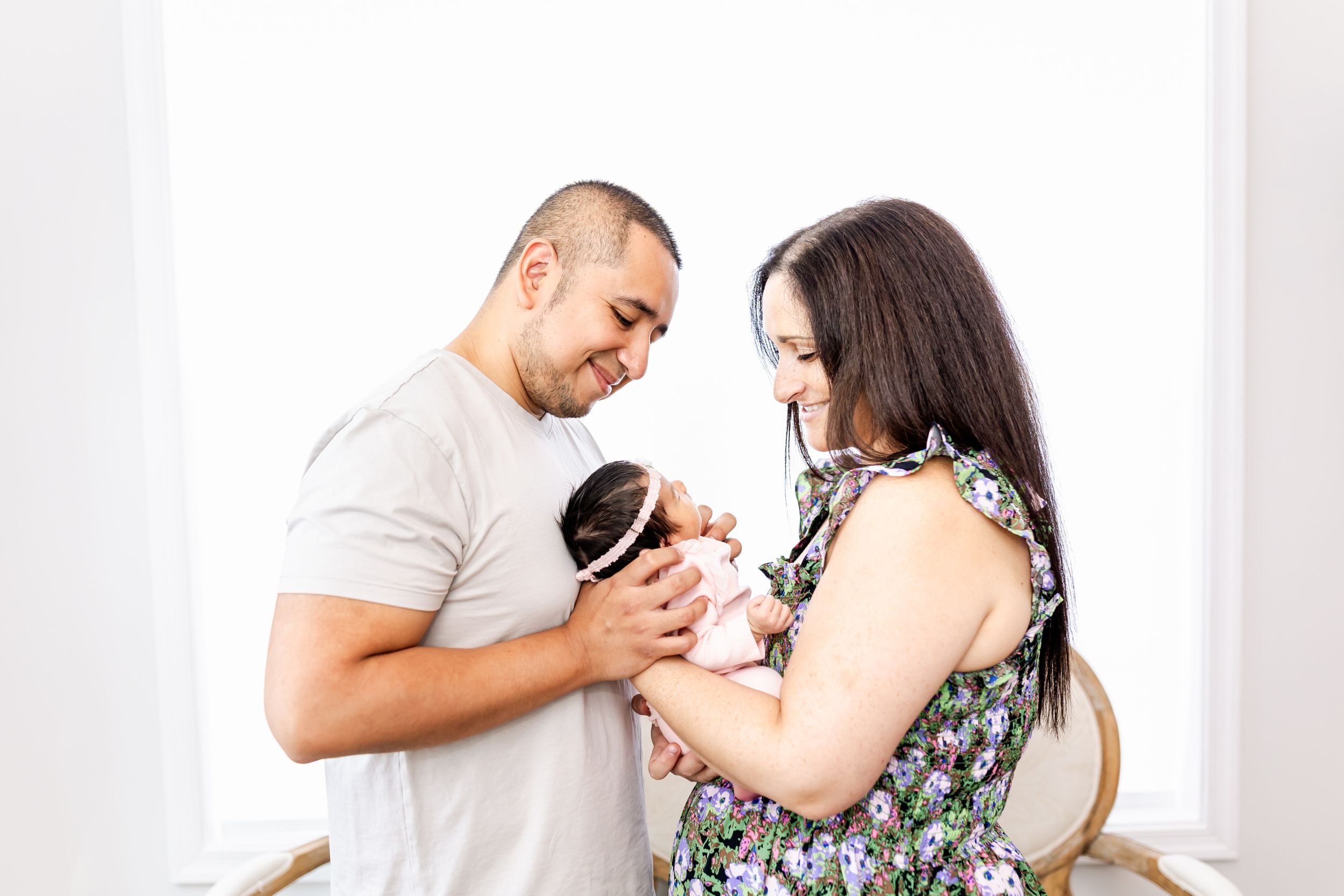 Couple holding and admiring tiny newborn baby indoors.
