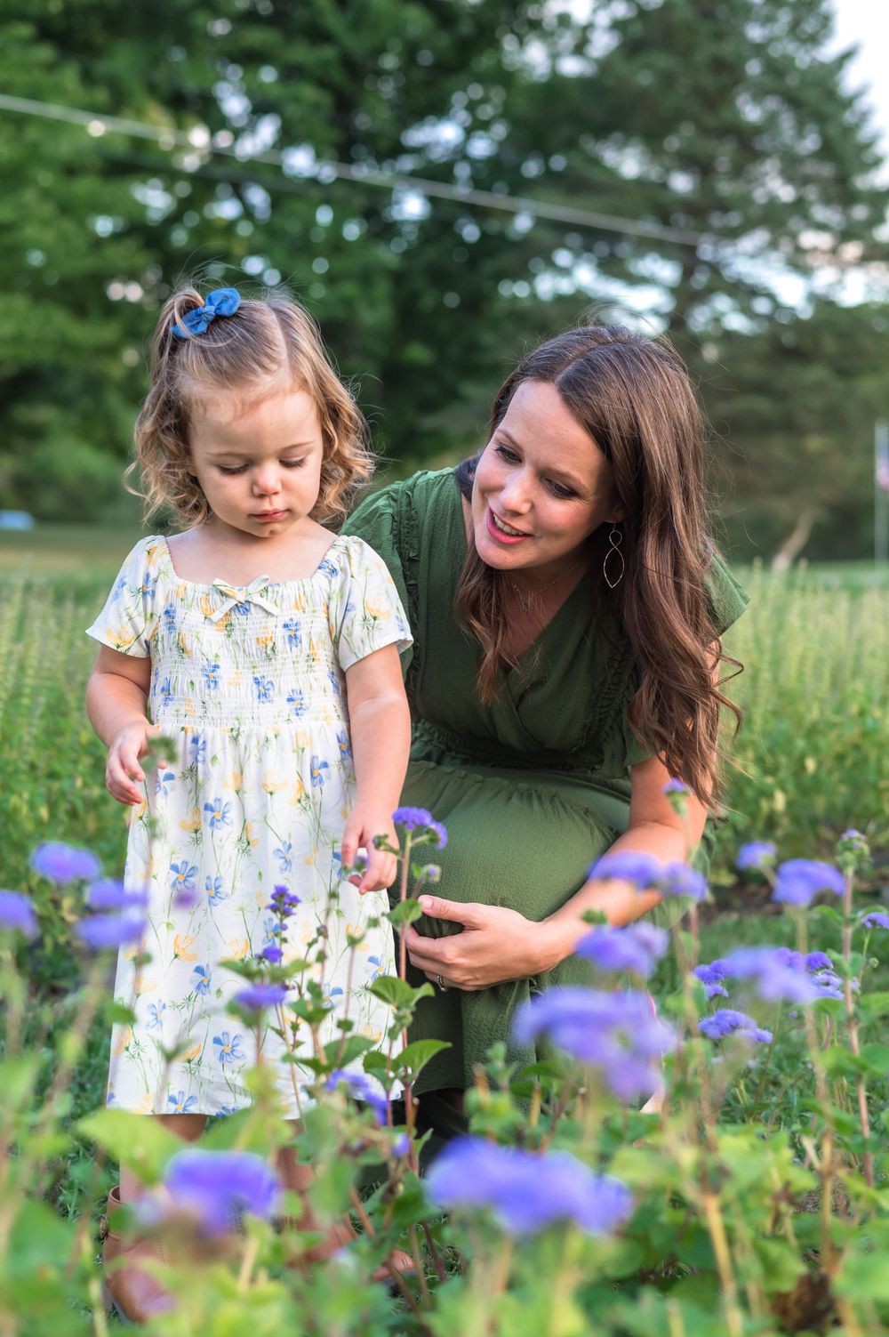 Two people admiring purple wildflowers in a lush summer garden setting.