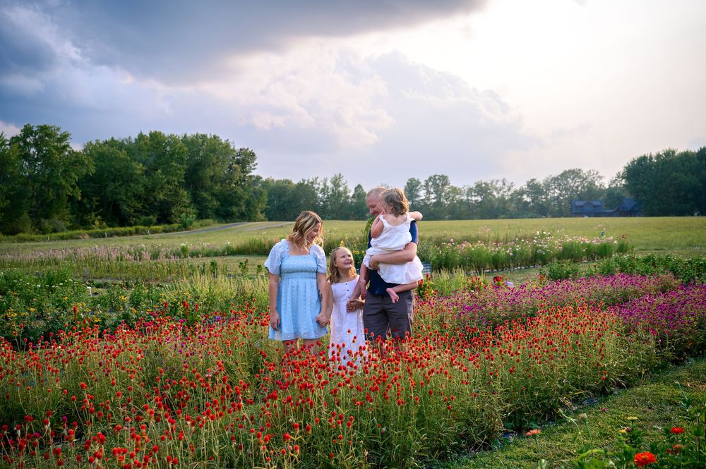 A group stands together in a vibrant wildflower meadow with pink and red blooms during golden hour.
