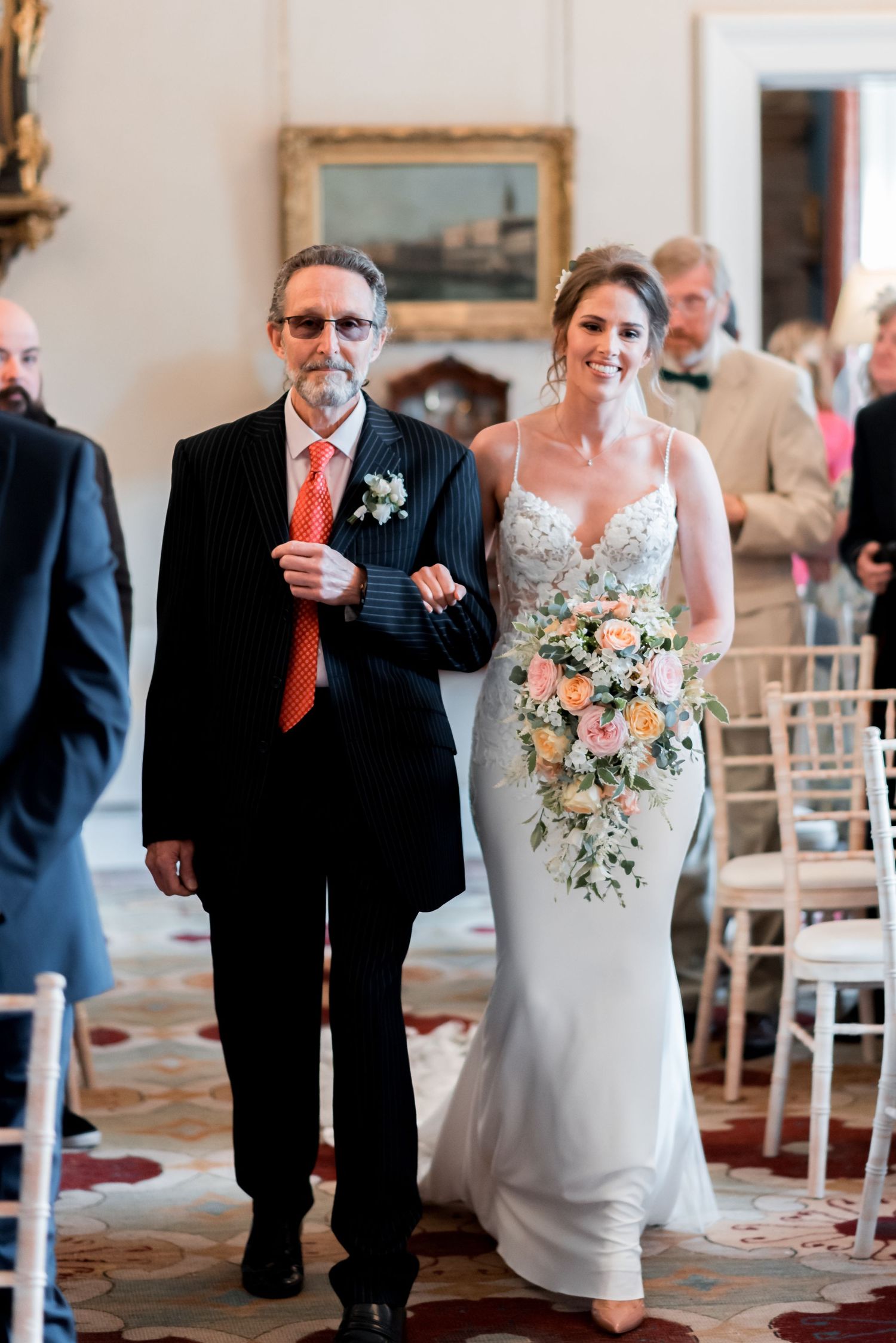 A wedding ceremony held in an elegant indoor venue with decorative carpeting and traditional white chairs.