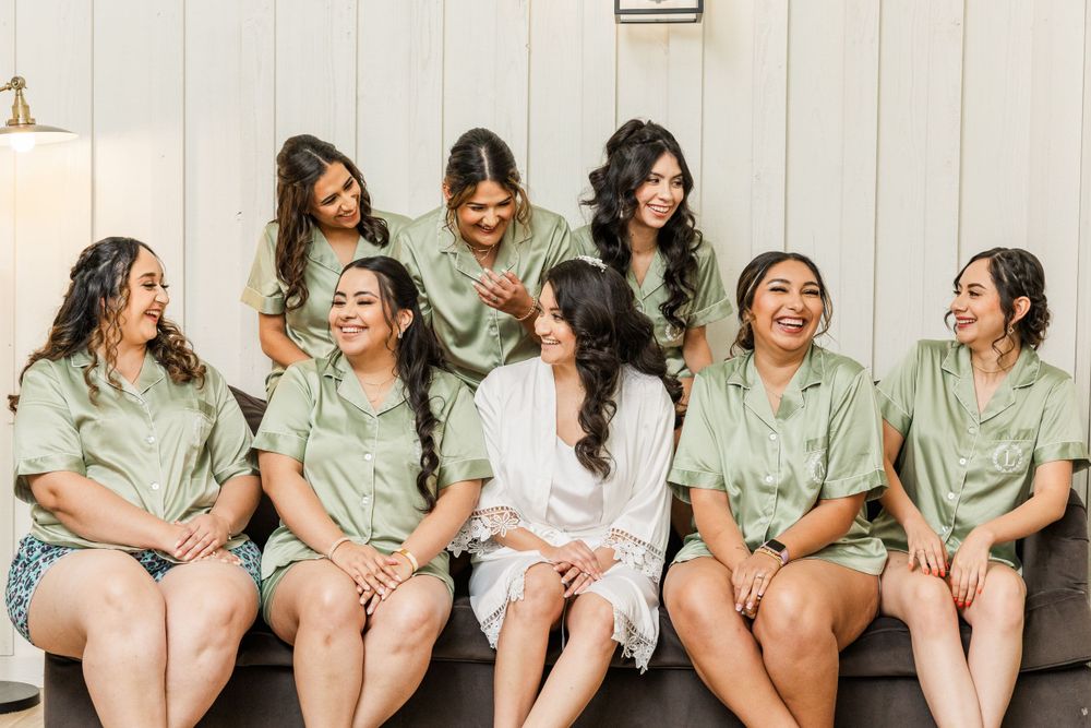 Group wearing matching mint green satin robes sitting together during wedding preparations.