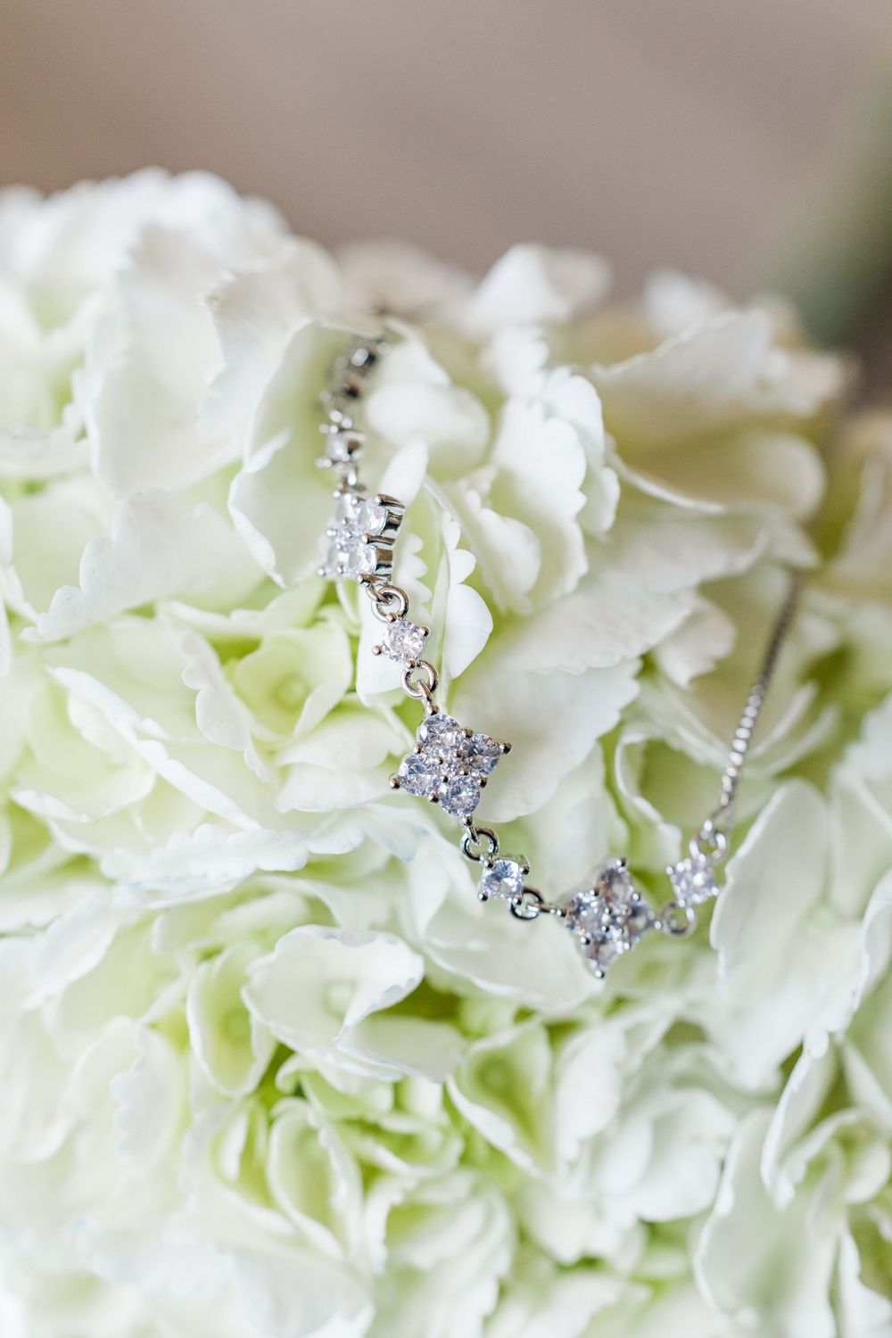 Delicate diamond necklace resting on white floral bouquet in soft focus.
