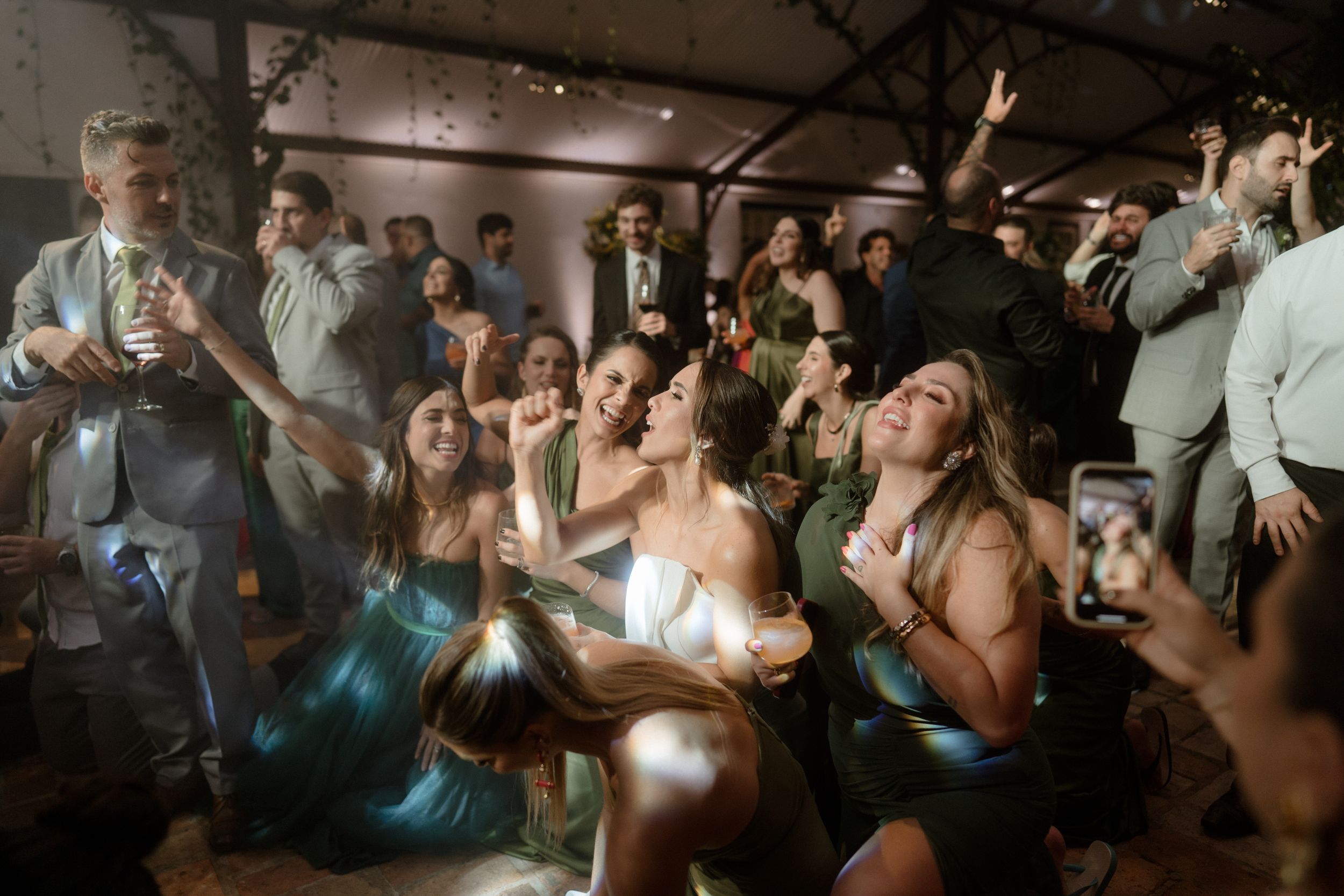 Wedding reception crowd cheering and celebrating on dance floor.