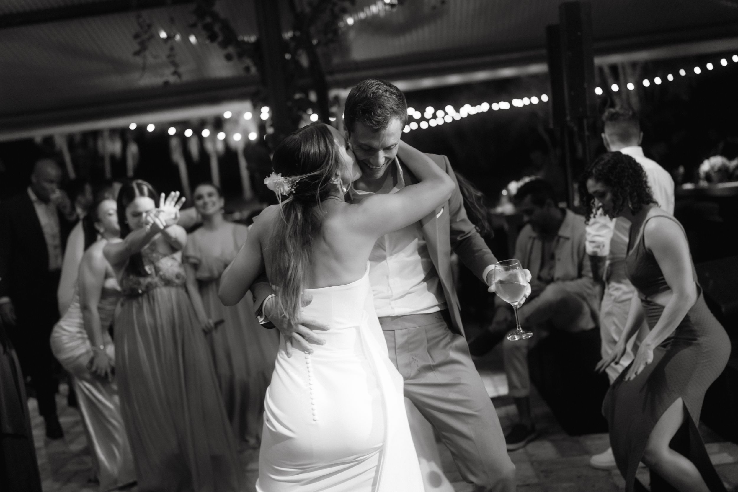Wedding guests dancing together on a dimly lit dance floor during evening celebration.