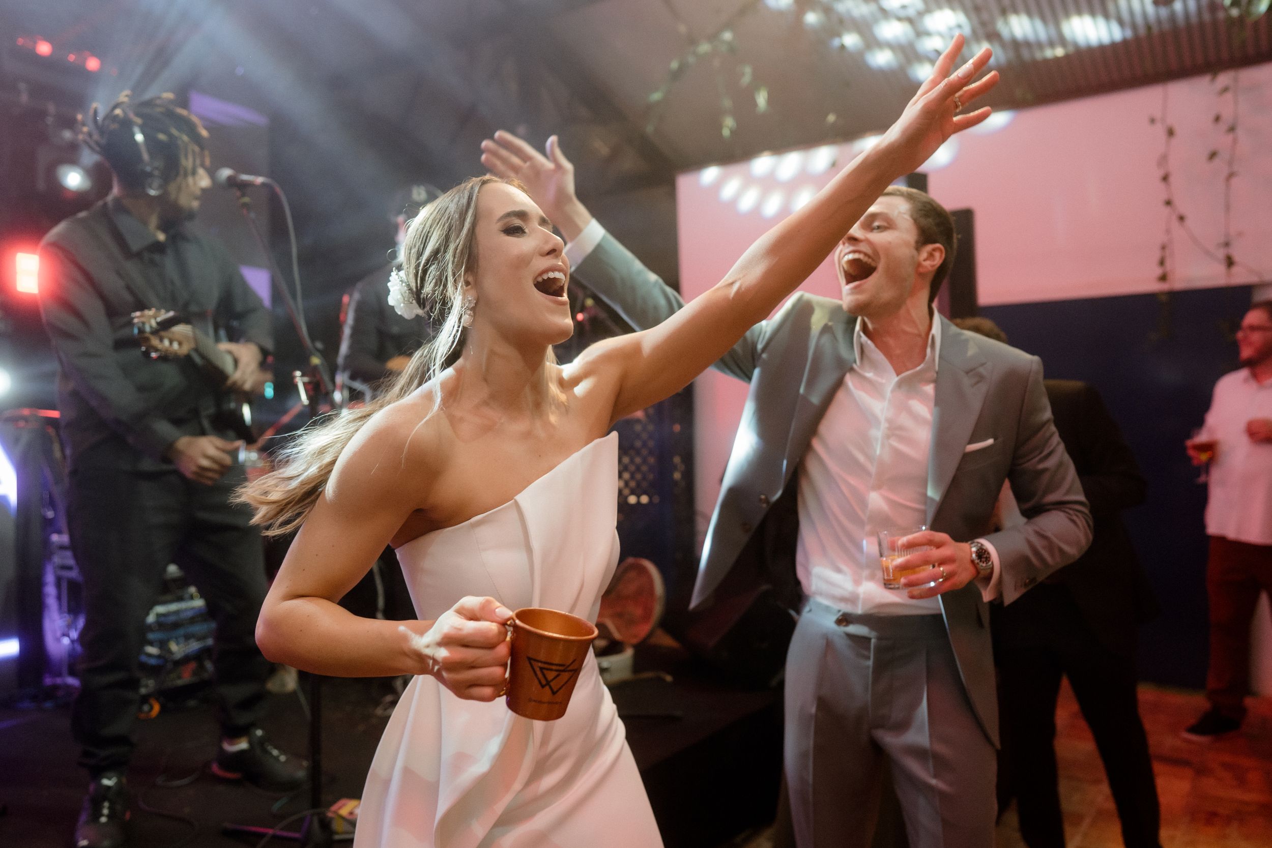 Guests dancing and celebrating at a festive indoor party with colorful lighting.