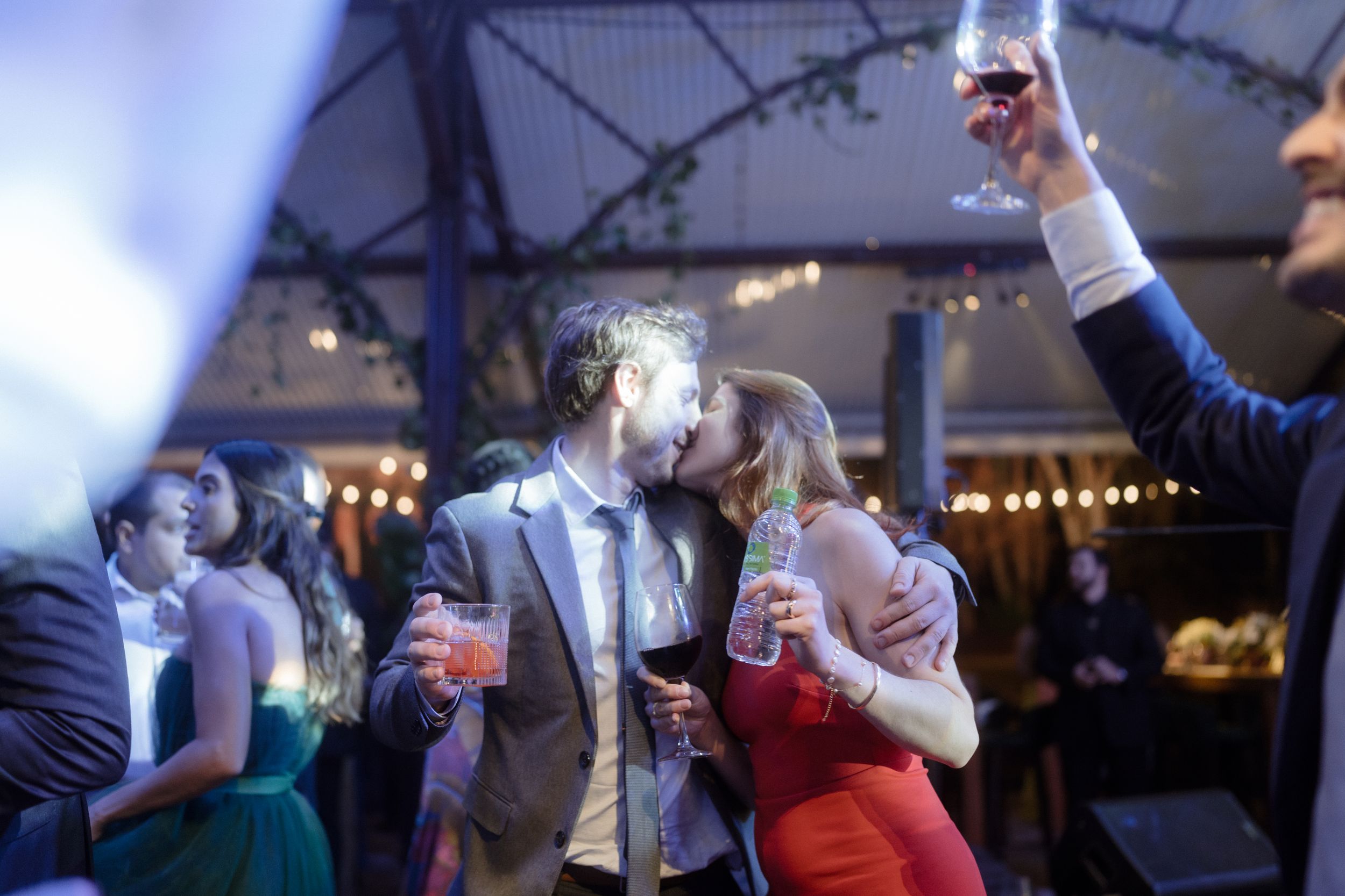 Party guests raising glasses in celebration under blue lighting.
