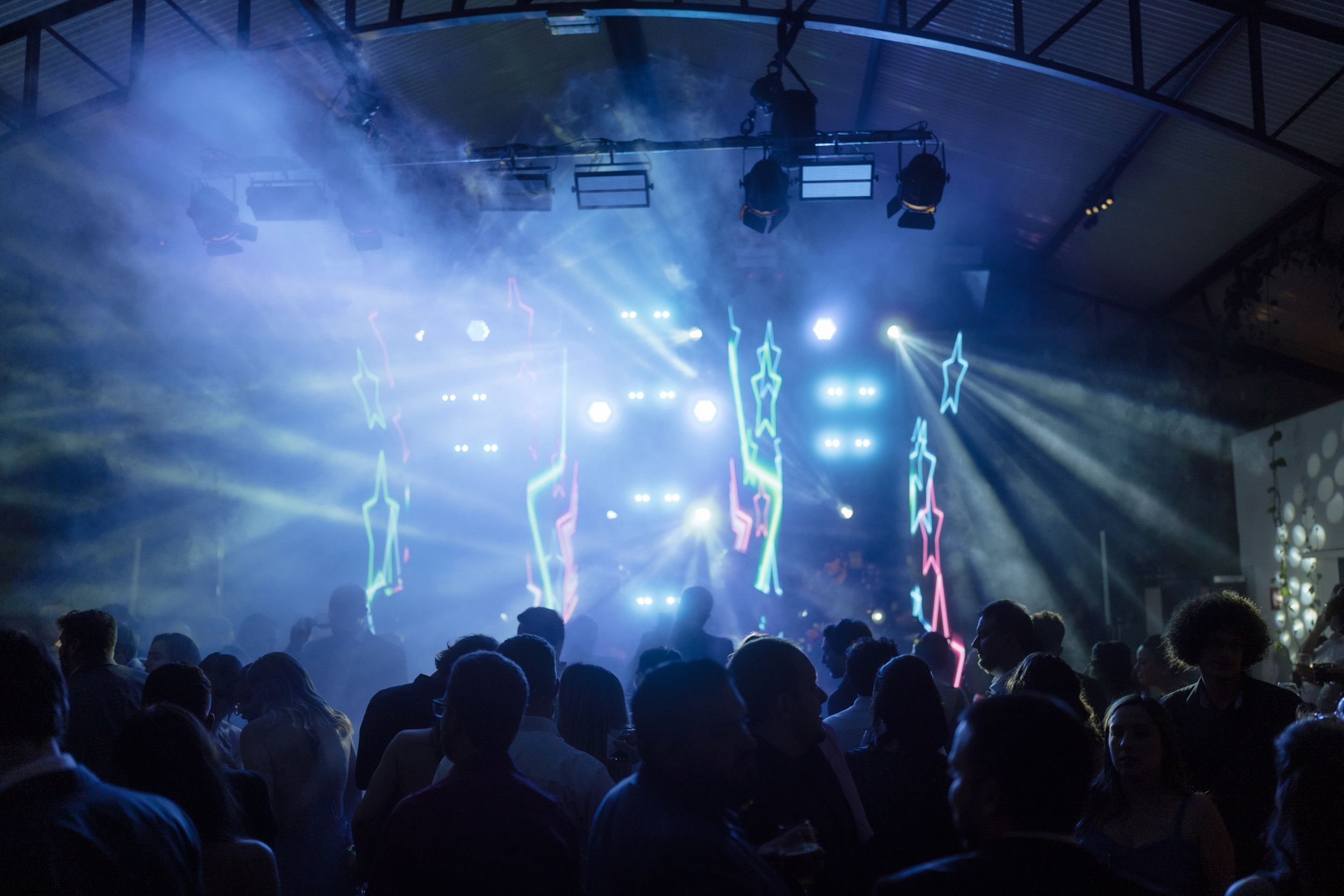 Silhouetted crowd dancing under atmospheric blue lighting at an indoor venue.