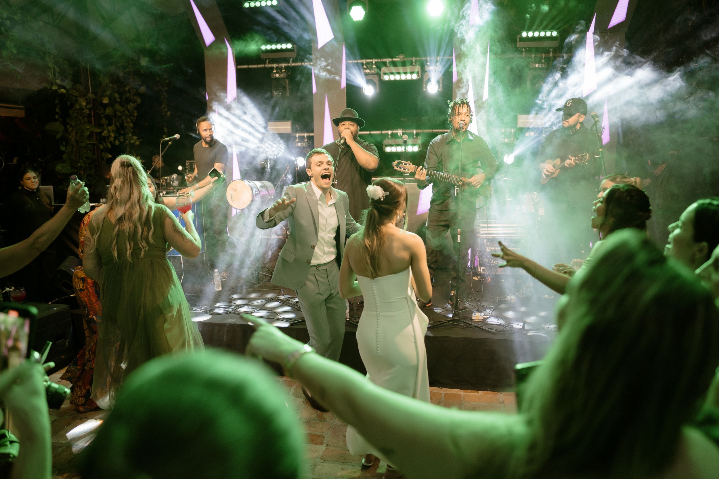Wedding celebration with fog machines and lights creating an energetic dance floor atmosphere.