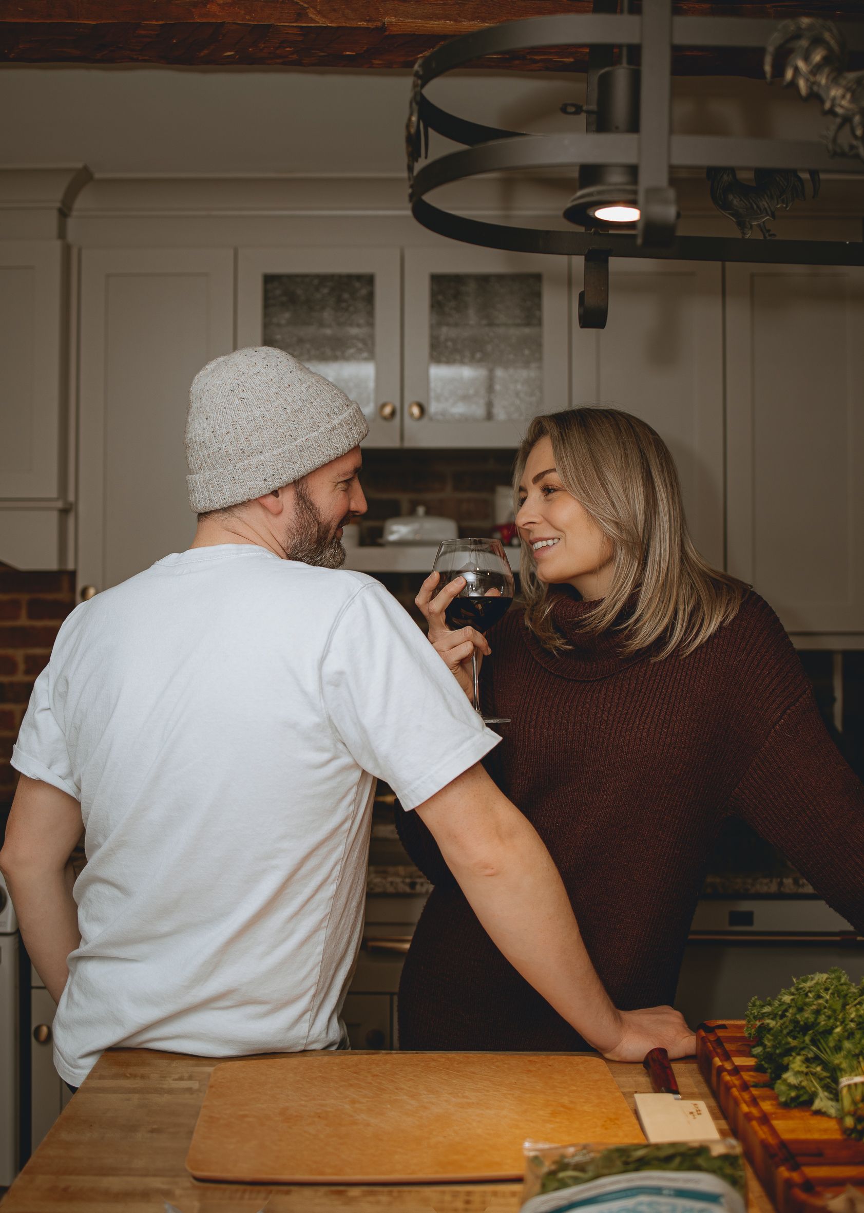 Couple sharing a moment while cooking in rustic kitchen with wine.