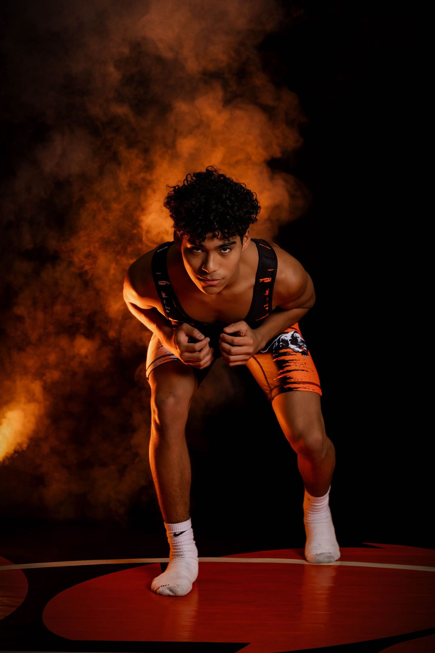 A football player poses in an orange jersey with number 2 and white pants against a dark background.