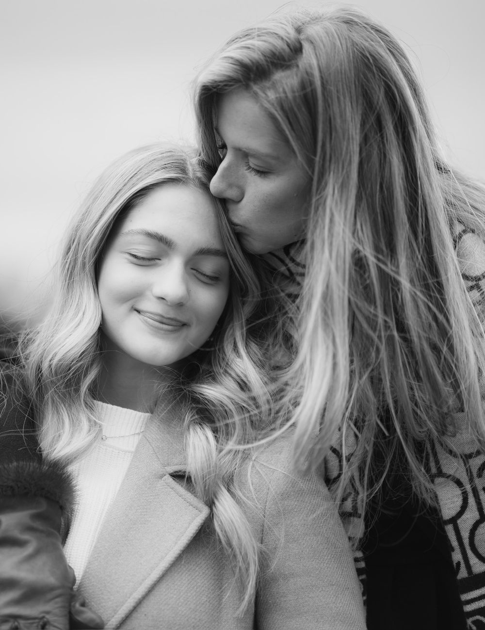 An intimate black and white portrait of two people sharing a tender moment.