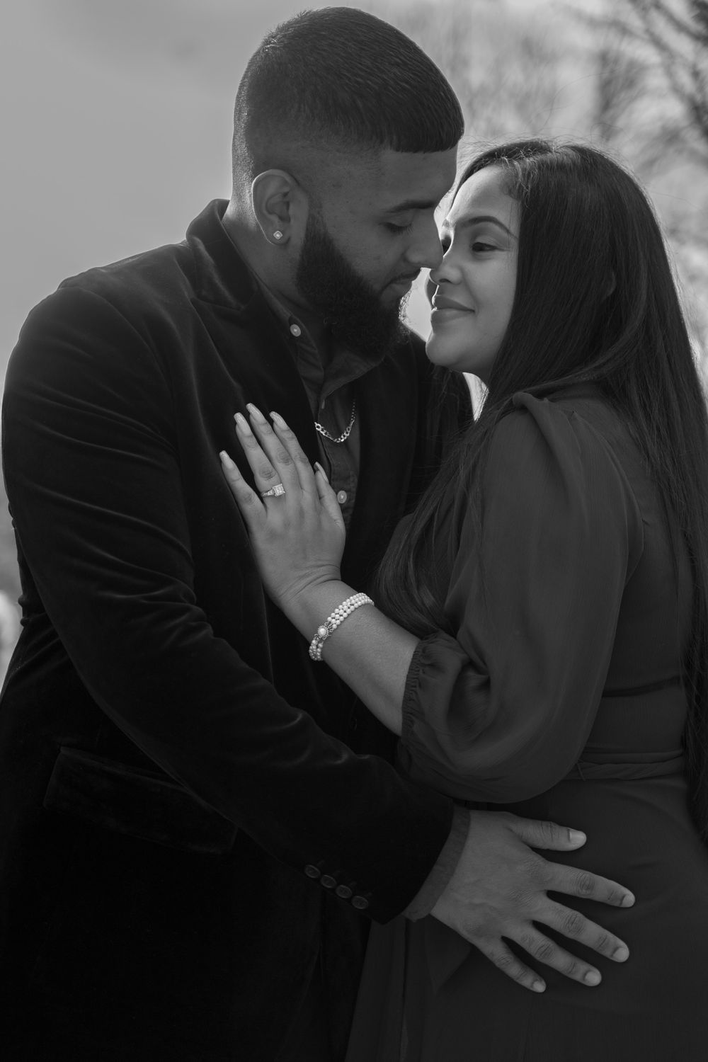 A romantic black and white portrait of an engaged couple in an intimate embrace.
