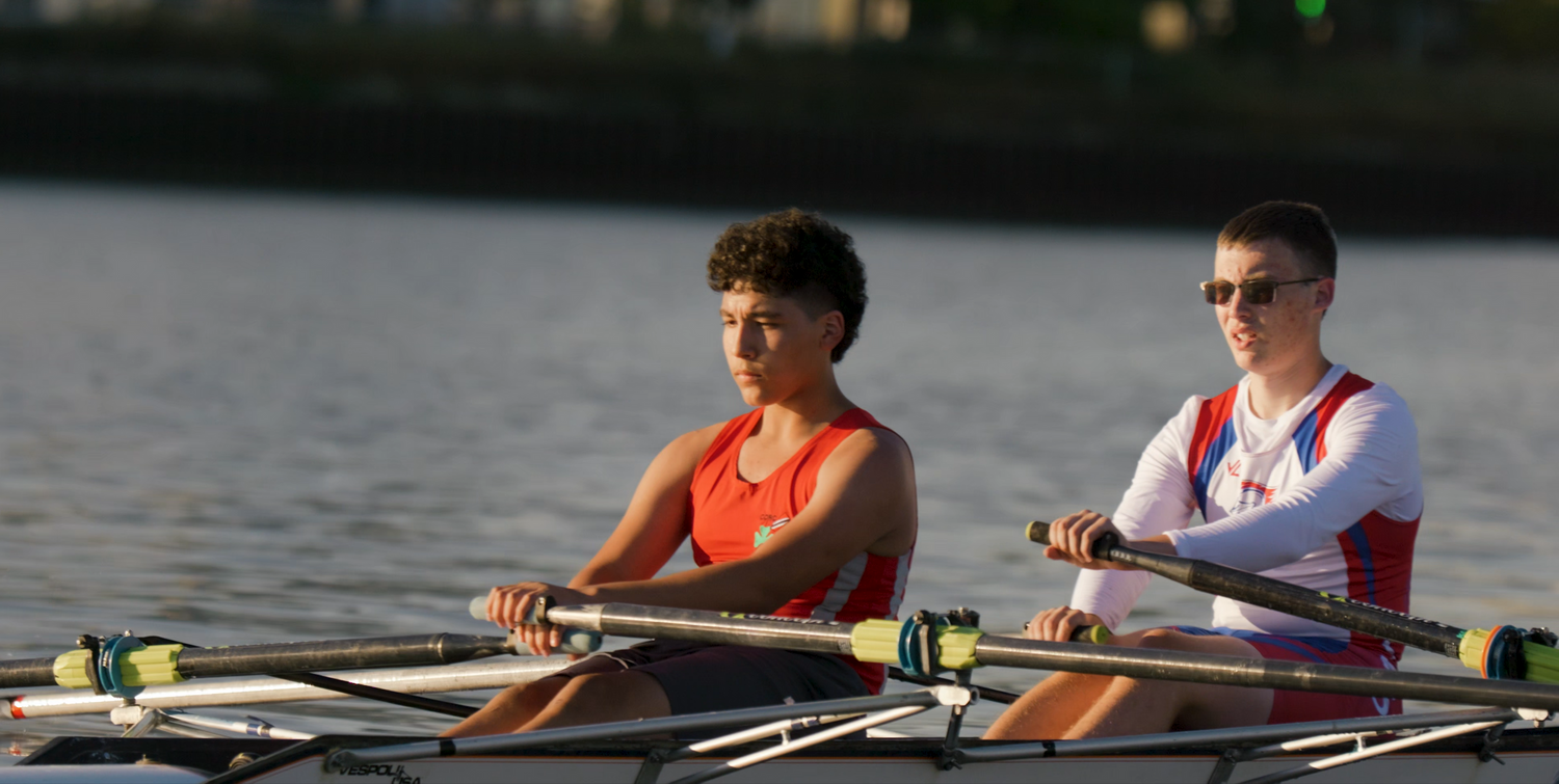 Two rowers practicing together on a lake during a sunny day in their racing shells.