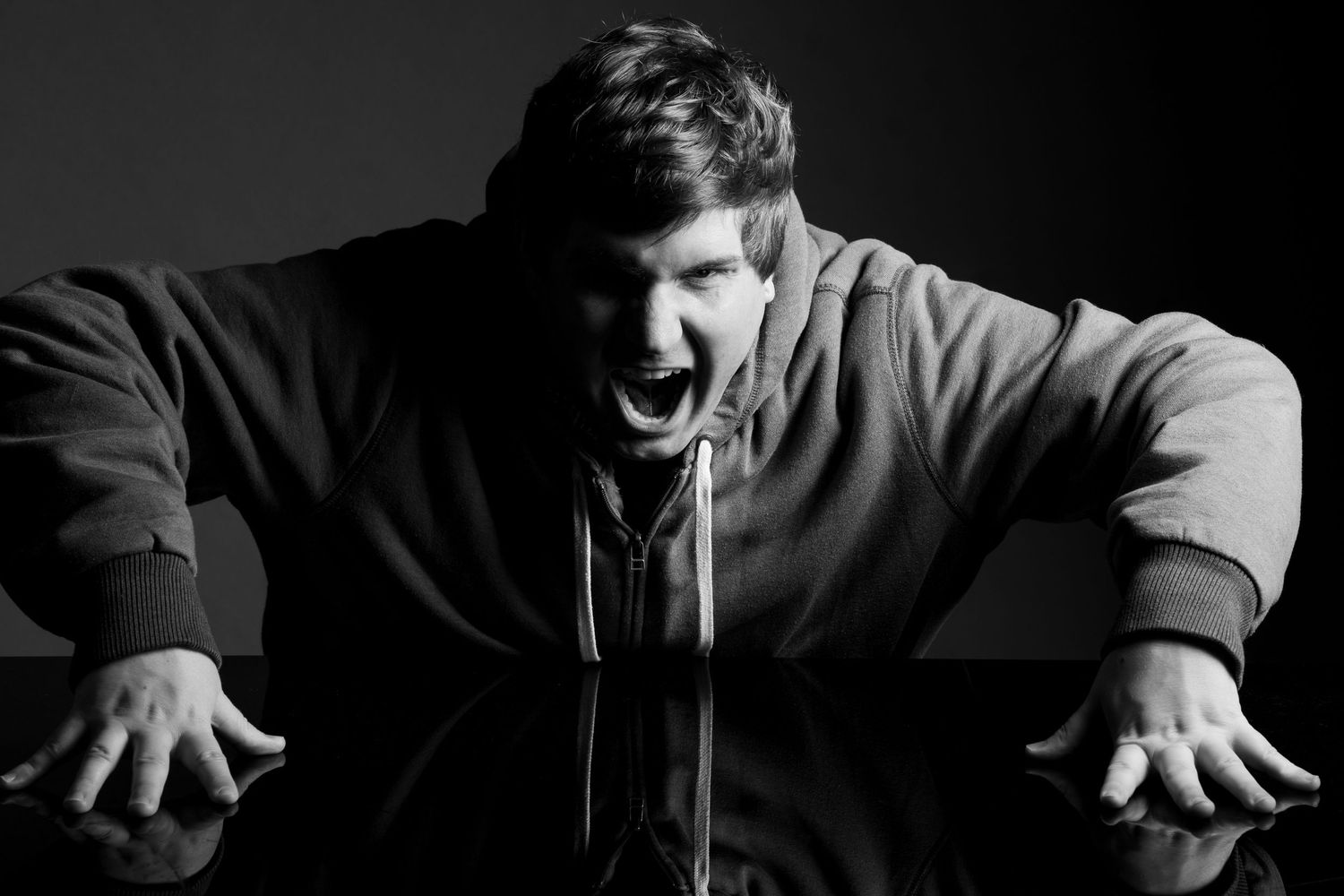Dramatic black and white portrait of person making expressive gesture.