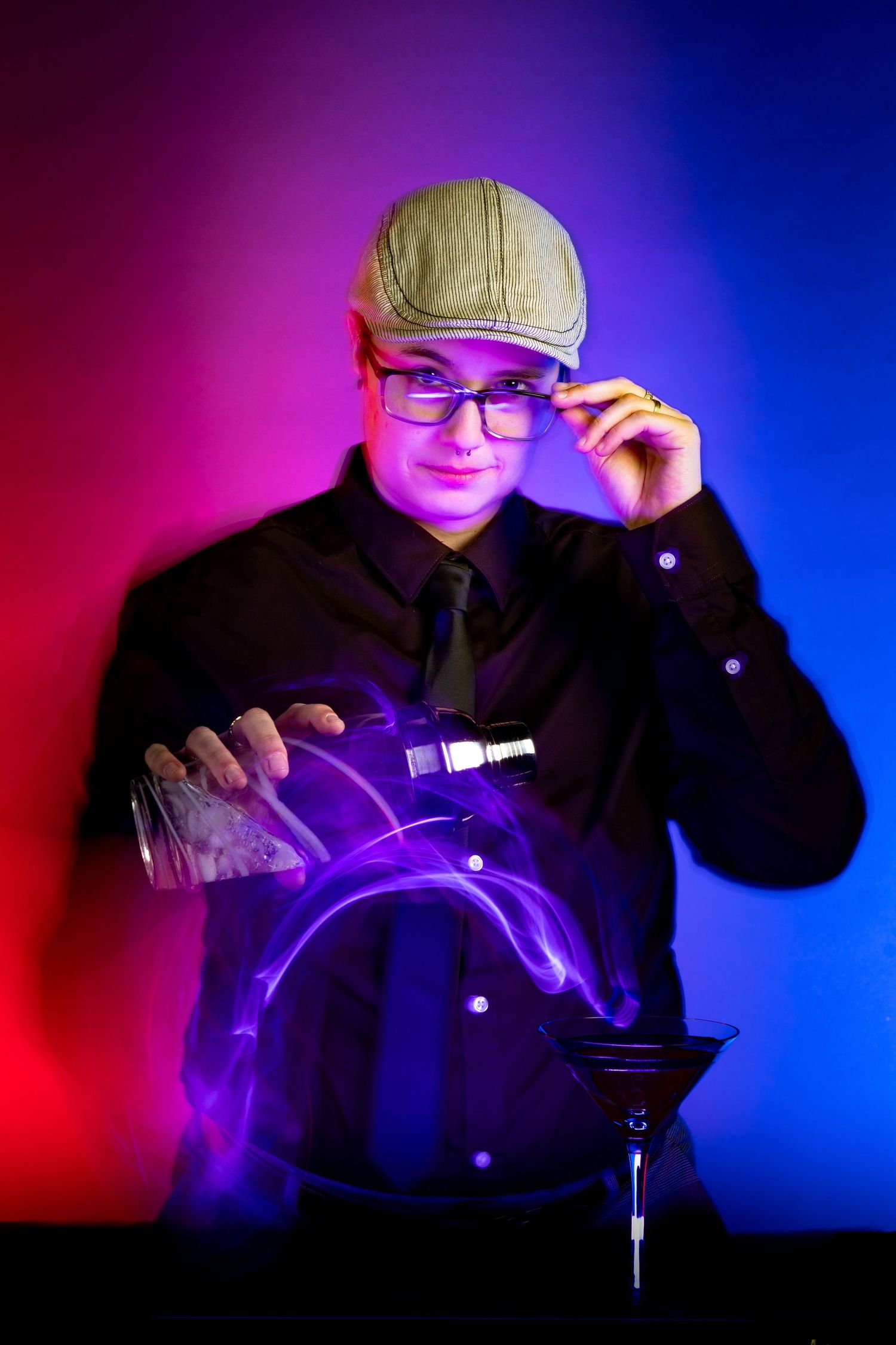 Bartender in cap and glasses mixing drinks with dramatic red and blue lighting.