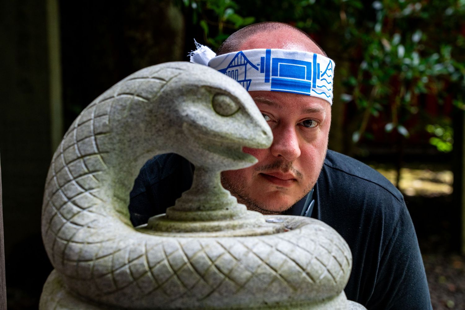 A playful moment captured with a decorative snake sculpture in a garden setting.