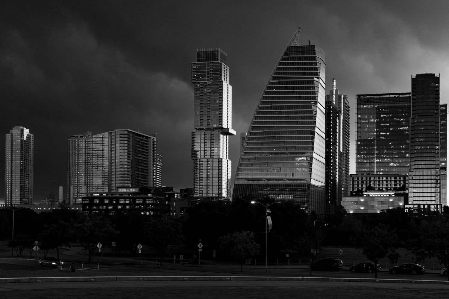 Modern skyscrapers in dramatic black and white against a stormy sky.