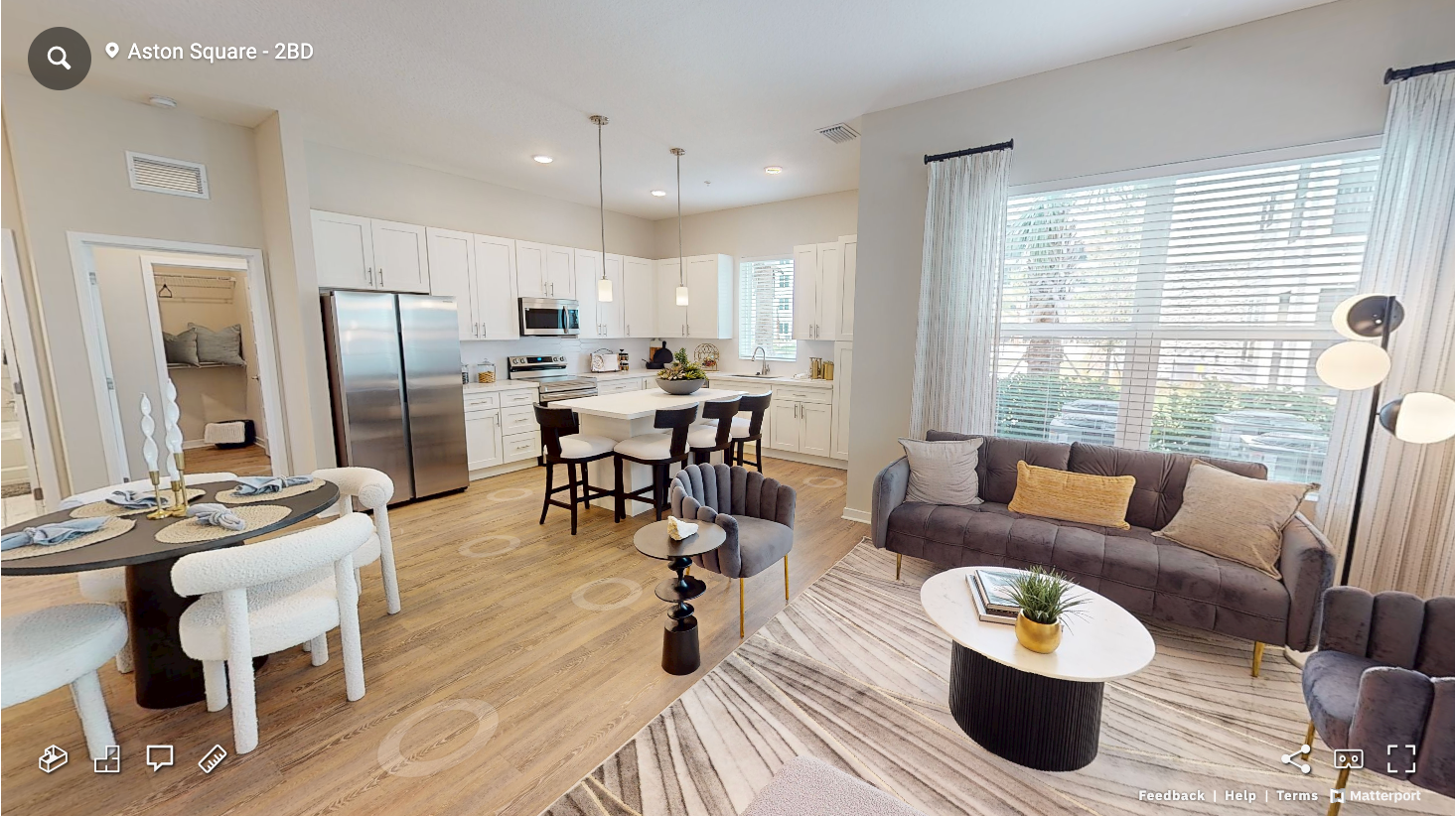 Modern open concept living room and kitchen with hardwood floors, stainless steel appliances, and contemporary furnishings.