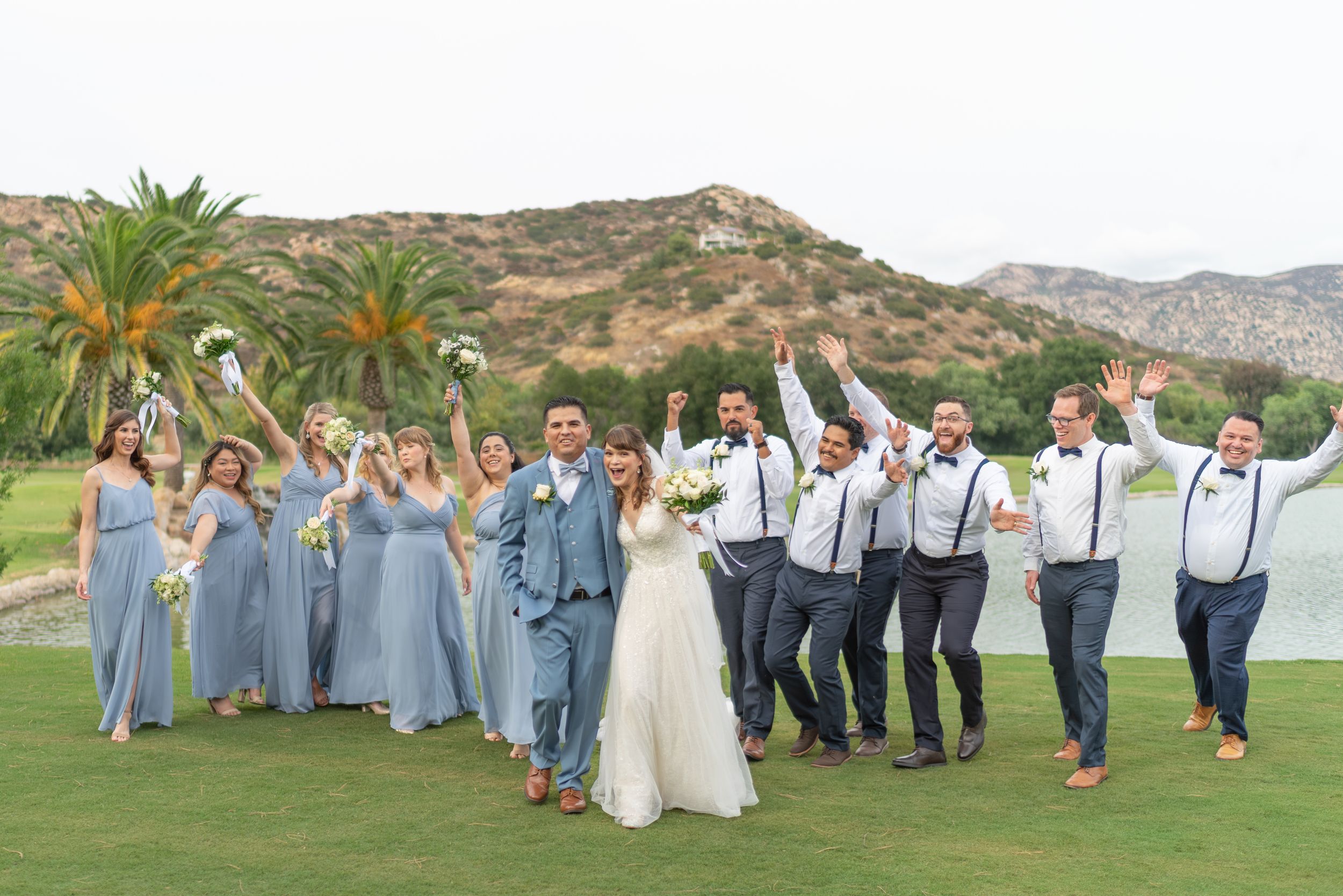 “Bride and groom celebrating with their wedding party at a scenic outdoor San Diego wedding. Fun, candid wedding photography capturing joyfu