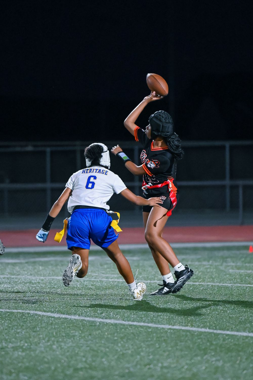Players diving for a loose football on the turf field during gameplay.
